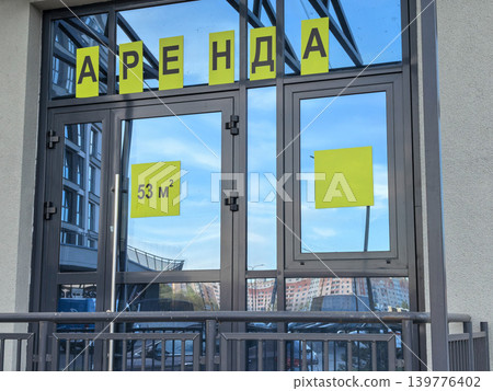 Commercial space for rent sign in Russian on glass storefront doors closeup 139776402
