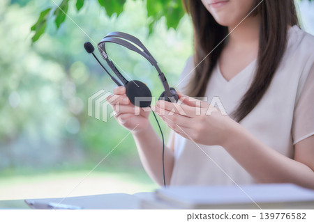 一位年輕女子一邊看著電腦一邊學習。 一位年輕女子一邊看著電腦一邊學習。 139776582