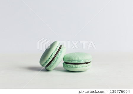 Two French macarons on a white wooden table. Mint macarons. White background. Two French macarons on a white wooden table. Mint macarons. White background. 139776604
