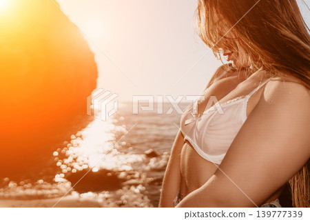 Woman lingerie sunset young female in white lace underwear standing by rocky coast at golden hour expressing serenity Woman lingerie sunset young female in white lace underwear standing by rocky coast at golden hour expressing serenity 139777339