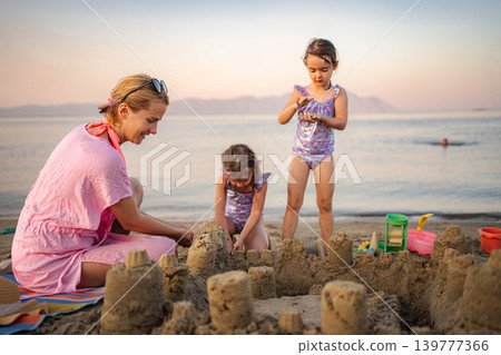 Mother and daughters building sandcastle on Greece beach during summer vacation 139777366