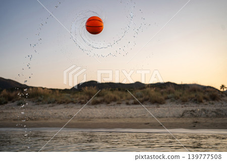 Spinning basketball splashing water at Greece beach during sunset 139777508