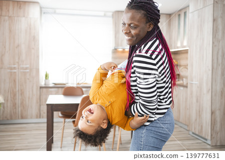Happy multiracial family playing together in their kitchen at home Happy multiracial family playing together in their kitchen at home 139777631