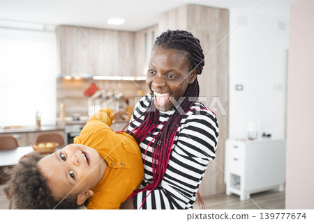 Joyful multiracial family playing together in a modern kitchen Joyful multiracial family playing together in a modern kitchen 139777674