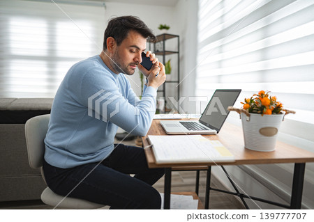 Man Sitting at Desk Talking on Cell Phone 139777707