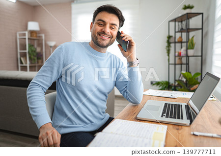 Man Sitting at Desk Talking on Cell Phone Man Sitting at Desk Talking on Cell Phone 139777711