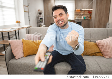 Man Sitting on Couch Holding Remote Control Man Sitting on Couch Holding Remote Control 139777747