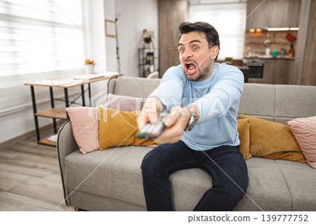 Man Sitting on Couch Holding Remote Man Sitting on Couch Holding Remote 139777752