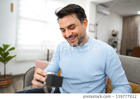 Man has opened the package and is looking at the new watch 139777812