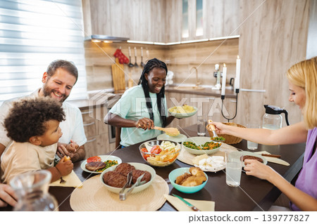 Family gathers for a lively meal in a cozy kitchen setting Family gathers for a lively meal in a cozy kitchen setting 139777827