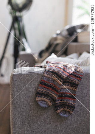 Hand knitted socks on the sofa in modern interior. Natural colors. Hand knitted socks on the sofa in modern interior. Natural colors. 139777923