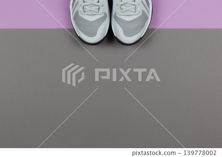 Grey sneakers on the violet and grey background. Concept for healthy lifestyle and everyday training. Grey sneakers on the violet and grey background. Concept for healthy lifestyle and everyday training. 139778002