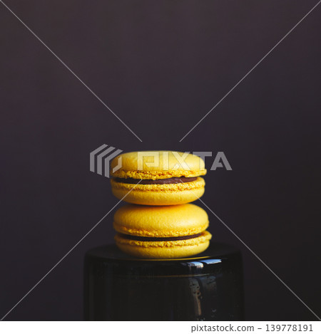 Two yellow french macarons on dark background. Banana macarons with chocolate cream. 139778191