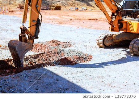 Excavator works on digging up soil to trench at construction site 139778370