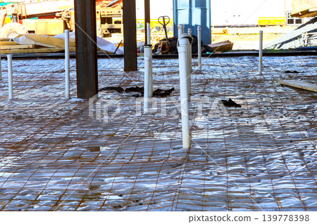 Workers prepare construction site with rebar pipes on flat surface for next stage of building. Workers prepare construction site with rebar pipes on flat surface for next stage of building. 139778398