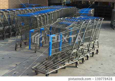 Shopping carts sit in row outside entrance of store waiting for customers to use them. Shopping carts sit in row outside entrance of store waiting for customers to use them. 139778428