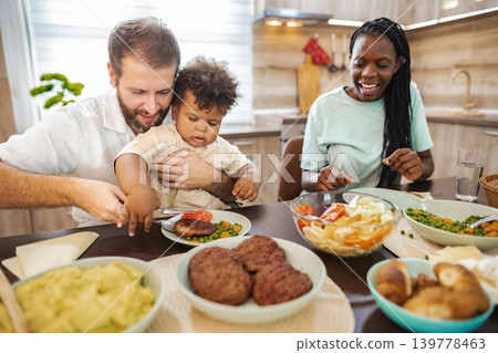 Family enjoying a homemade dinner together in a cozy kitchen Family enjoying a homemade dinner together in a cozy kitchen 139778463