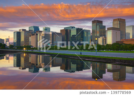 Tokyo, Japan - Oct 1 2024, panoramic view of skyscrapers of Chiyoda district, with a moat in foreground with mirror-like water reflecting buildings and sky, and colorful clouds in sky at sunset, Tokyo Tokyo, Japan - Oct 1 2024, panoramic view of skyscrapers of Chiyoda district, with a moat in foreground with mirror-like water reflecting buildings and sky, and colorful clouds in sky at sunset, Tokyo 139778569