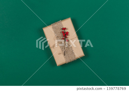 Craft gift box with branch of red berries on dark green background. Holiday eco-friendly concept. Craft gift box with branch of red berries on dark green background. Holiday eco-friendly concept. 139778769