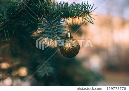 Fluffy branches of a spruce or fir-tree with christmas sparkle golden ball. Christmas wallpaper or postcard concept. Fluffy branches of a spruce or fir-tree with christmas sparkle golden ball. Christmas wallpaper or postcard concept. 139778776