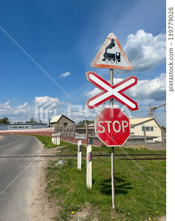Railroad crossing warning and stop sign on suburban road with railway transportation symbols Railroad crossing warning and stop sign on suburban road with railway transportation symbols 139779026