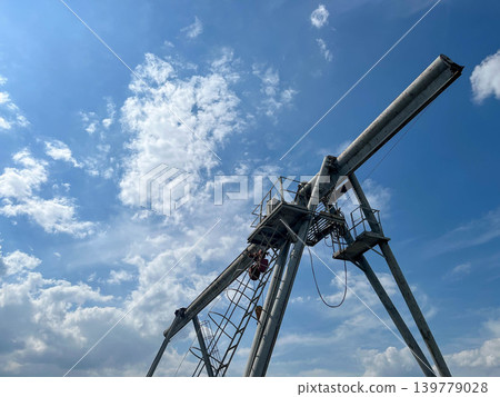 Heavy industrial gantry crane against blue sky at cargo loading and warehouse operation site Heavy industrial gantry crane against blue sky at cargo loading and warehouse operation site 139779028