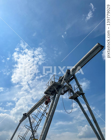 Industrial gantry crane structure reaching into blue sky at cargo and warehouse facility Industrial gantry crane structure reaching into blue sky at cargo and warehouse facility 139779029