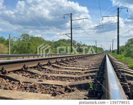 Railway tracks stretching into distance with electric infrastructure under dramatic cloudy sky Railway tracks stretching into distance with electric infrastructure under dramatic cloudy sky 139779031