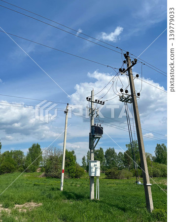 Electrical power lines and utility poles in rural landscape under dramatic cloudy blue sky Electrical power lines and utility poles in rural landscape under dramatic cloudy blue sky 139779033
