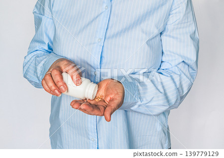 Senior woman pouring pills from a bottle into her hand for daily health and self care 139779129