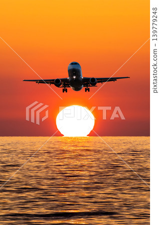 Passenger plane landing over the sea against the backdrop of picturesque sundown Passenger plane landing over the sea against the backdrop of picturesque sundown 139779248