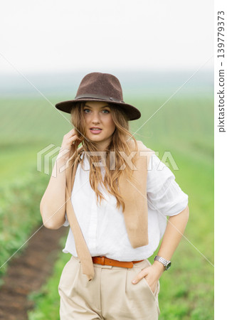Woman in hat smiling while walking outdoors Woman in hat smiling while walking outdoors 139779373