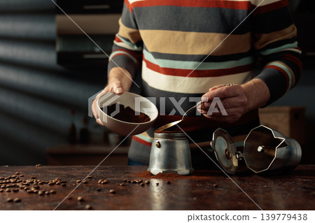 A man in a striped jumper is about to make coffee in an old Italian coffee maker. A man in a striped jumper is about to make coffee in an old Italian coffee maker. 139779438