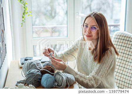 Woman knitting wool yarn at home, creating handmade handicraft clothes Woman knitting wool yarn at home, creating handmade handicraft clothes 139779474