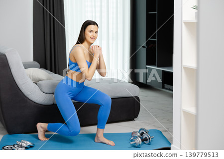 Woman performing lunges for home workout fitness Woman performing lunges for home workout fitness 139779513