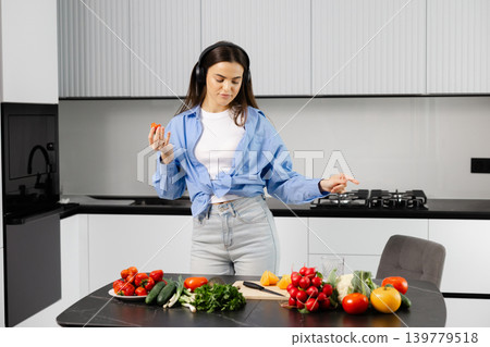 Woman enjoying healthy cooking in modern kitchen listening music 139779518