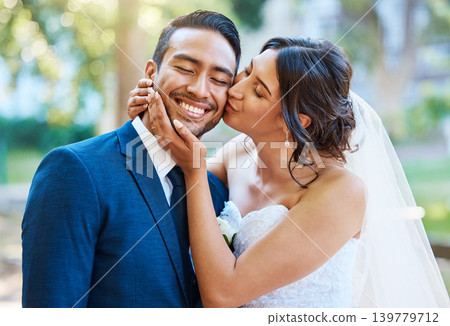 Kiss, smile and couple at wedding outdoor for marriage, love or trust with happiness in nature. Bride, groom and people with affection, partner and support for connection with romance in park Kiss, smile and couple at wedding outdoor for marriage, love or trust with happiness in nature. Bride, groom and people with affection, partner and support for connection with romance in park 139779712