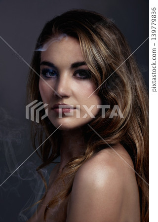 Woman, portrait and makeup, beauty and smoke with hair, cosmetics and color highlights on grey background. Serious model, edgy with haircare and vapor, cosmetology and face with mist or fog in studio 139779836