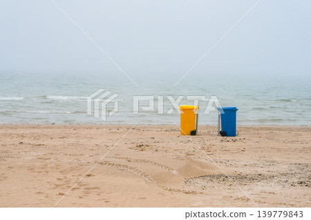 Colorful recycling bins on foggy Baltic Sea beach during calm misty morning in Latvia coastline 139779843