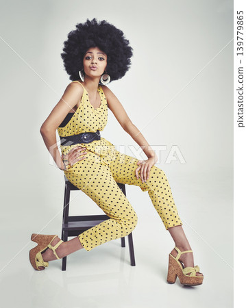 Black woman, portrait and relax on chair in fashion, yellow jumpsuit or high heels on a gray studio background. African female person with afro, makeup or jewelry in beauty or style on mockup space Black woman, portrait and relax on chair in fashion, yellow jumpsuit or high heels on a gray studio background. African female person with afro, makeup or jewelry in beauty or style on mockup space 139779865