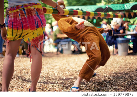 Limbo, game and person at party outdoor with balance and playing at a music festival, event or challenge. Fun, people and outdoor in woods, forest or person in social activity at party in bear suit Limbo, game and person at party outdoor with balance and playing at a music festival, event or challenge. Fun, people and outdoor in woods, forest or person in social activity at party in bear suit 139779872