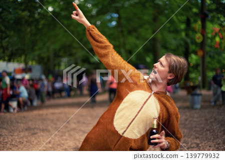 Halloween, costume and man with beer to drink at happy celebration outdoor in bear outfit. Animal, suit and person pointing to trees with lager, bottle and drinking alcohol in park at festival Halloween, costume and man with beer to drink at happy celebration outdoor in bear outfit. Animal, suit and person pointing to trees with lager, bottle and drinking alcohol in park at festival 139779932