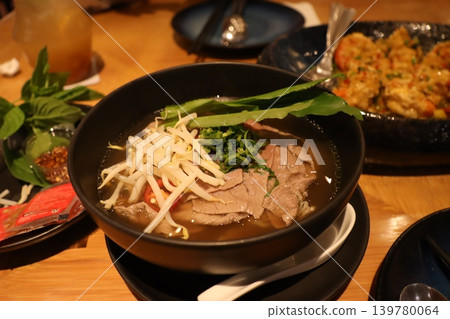 Steaming Bowl of Beef Noodle Soup with Fresh Garnishes Steaming Bowl of Beef Noodle Soup with Fresh Garnishes 139780064