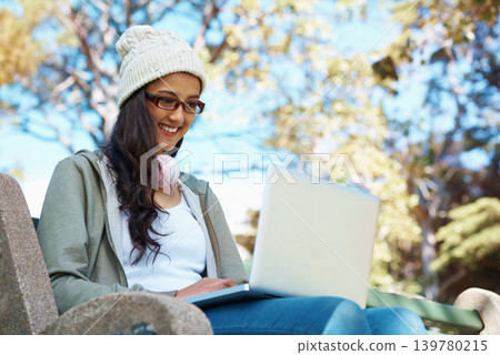 Woman, typing and college student on laptop in park with research, project or learning on campus. University, education and girl reading online with ebook on computer and study in garden with nature 139780215