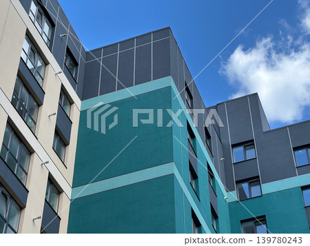 New apartment building with multiple stories stands strong against the blue sky with few clouds. Construction is nearly complete New apartment building with multiple stories stands strong against the blue sky with few clouds. Construction is nearly complete 139780243