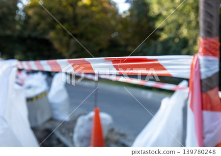 Red tape shows people to be careful as workers handle construction equipment near the road in the city during the afternoon Red tape shows people to be careful as workers handle construction equipment near the road in the city during the afternoon 139780248