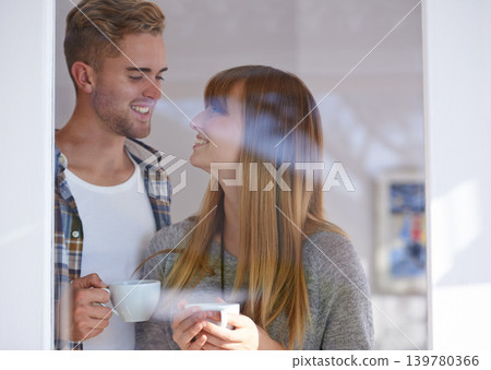 Couple, morning and drinking coffee by window and love on weekend, romance and hot tea at home. Happy people, bonding and peaceful or relaxation, commitment and loyalty to marriage or relationship Couple, morning and drinking coffee by window and love on weekend, romance and hot tea at home. Happy people, bonding and peaceful or relaxation, commitment and loyalty to marriage or relationship 139780366