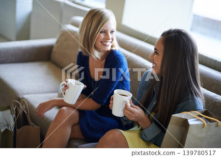Friends, women and drinking coffee after retail shopping while resting on the sofa at home. Female people, smiling and bonding with care to relax with tea drinks and conversation after buying style Friends, women and drinking coffee after retail shopping while resting on the sofa at home. Female people, smiling and bonding with care to relax with tea drinks and conversation after buying style 139780517