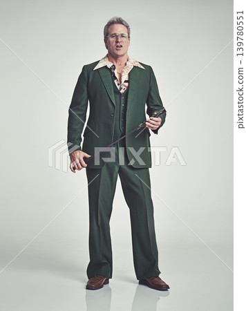 Mature, man and serious with fashion in studio, suit and grey background with riding crop. Tuxedo, elegance and retro with unique style and formal in expensive clothes, classy and fashionable Mature, man and serious with fashion in studio, suit and grey background with riding crop. Tuxedo, elegance and retro with unique style and formal in expensive clothes, classy and fashionable 139780551