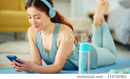 Smartphone, yoga and headphones of woman typing on chat app for fitness communication, social media update or blog writing wellness. Pilates girl with exercise gear and technology in home living room Smartphone, yoga and headphones of woman typing on chat app for fitness communication, social media update or blog writing wellness. Pilates girl with exercise gear and technology in home living room 139780962